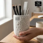Person holding a handcrafted white concrete pen holder to showcase its premium finish, compact size and modern design.
